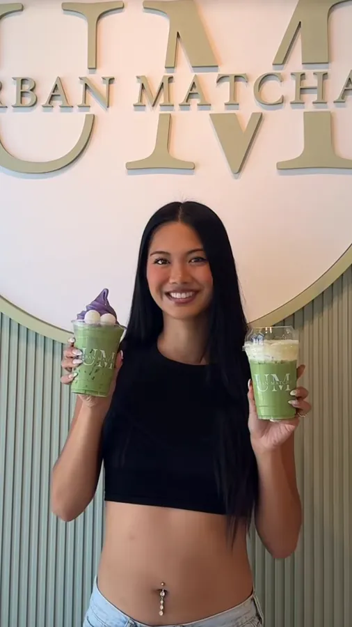 A creator holding two matcha drinks in front of the Urban Matcha sign, from a reel by @eatwithsie